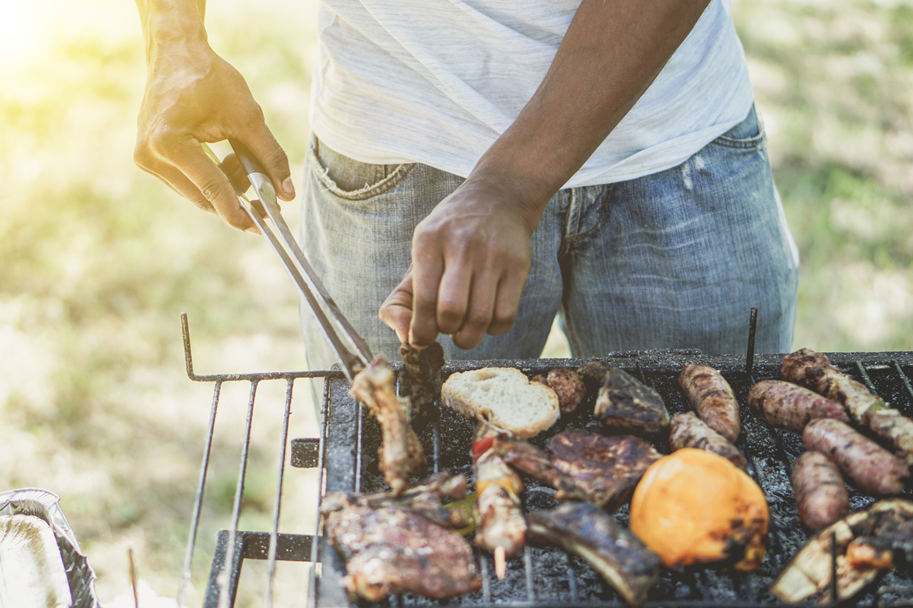 american man cooking meat on barbecue
